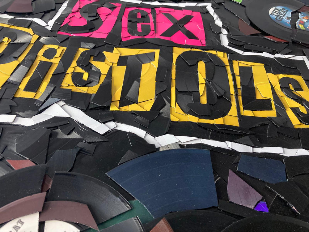 Ed Chapman mosaic artwork featuring the Sex Pistols logo created entirely from destroyed Sex Pistols vinyl records, with fractured black discs and colourful record labels forming a bold punk-inspired composition.