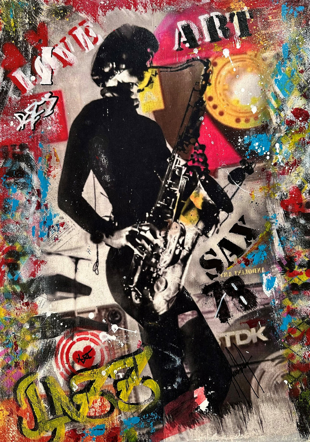Joseph Andolini (Andolini Art) – Sax Girl, a vibrant mixed media collage on art paper featuring a monochrome female saxophonist mid-performance, layered with graffiti text, stencil lettering, and bold splashes of colour. Red graffiti hearts, yellow accents, and blue sprays surround the figure, merging music and street art energy in a jazz-inspired tribute.