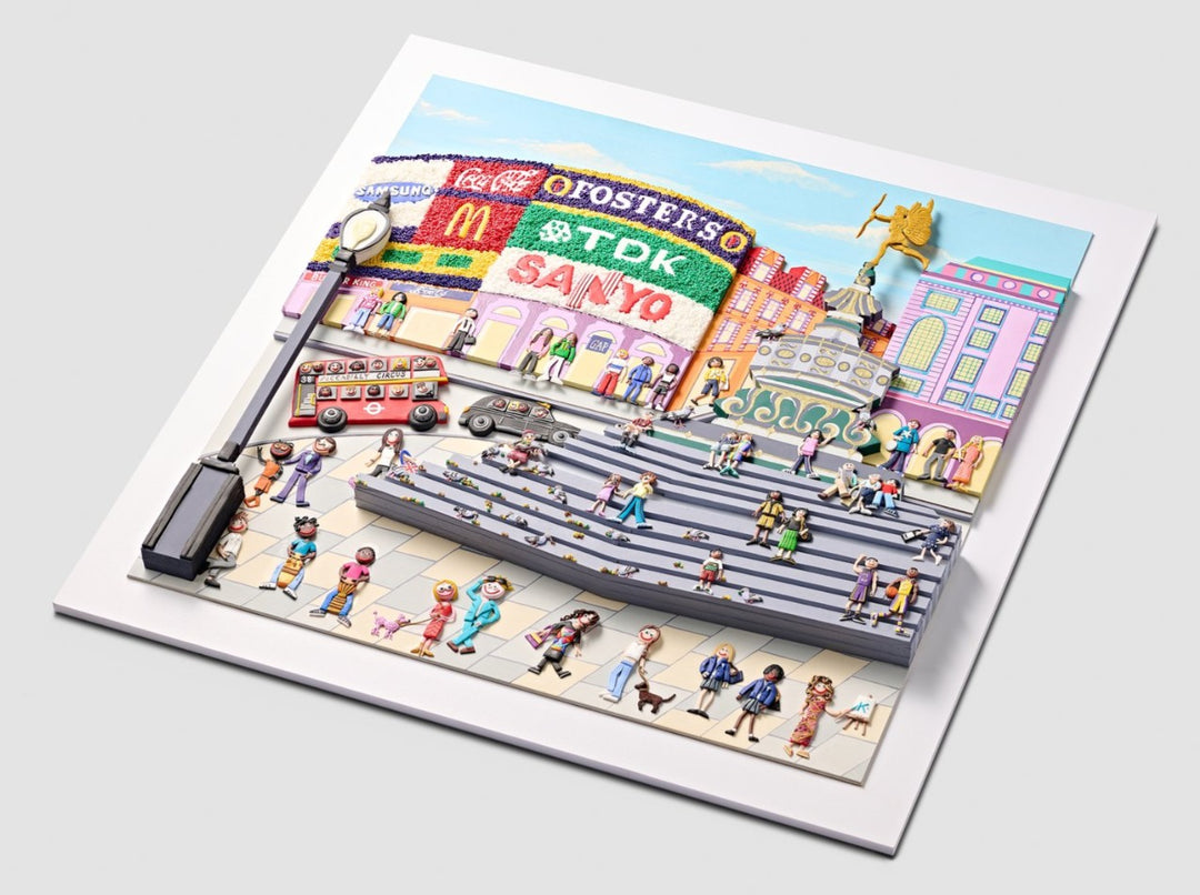 A vibrant, three-dimensional polymer clay artwork of Piccadilly Circus, featuring the iconic curved billboard with brands like Coca-Cola, McDonald’s, and TDK rendered in colourful textured beads. The street scene below includes a classic red double-decker bus marked “38 Piccadilly Circus,” a London black cab, and crowds of joyful figures in bright handmade outfits. Sculpted pigeons dot the grey stone steps beneath the Shaftesbury Memorial Fountain with a golden winged Eros above. 