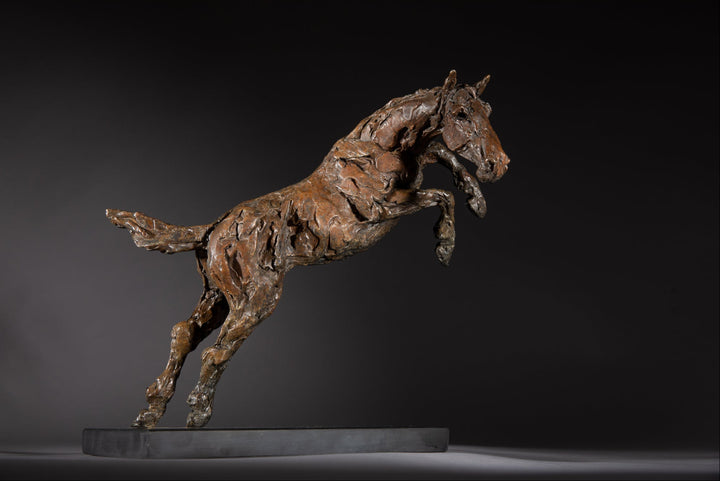 Bronze sculpture of a powerful jumping horse titled Loving Life (Hunter), captured mid-leap with expressive musculature and dynamic energy, mounted on a dark oval base and photographed against a neutral backdrop.