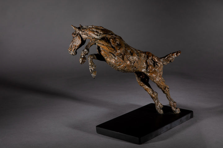 Bronze sculpture of a powerful jumping horse titled Loving Life (Hunter), captured mid-leap with expressive musculature and dynamic energy, mounted on a dark oval base and photographed against a neutral backdrop.