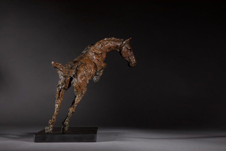 Bronze sculpture of a powerful jumping horse titled Loving Life (Hunter), captured mid-leap with expressive musculature and dynamic energy, mounted on a dark oval base and photographed against a neutral backdrop.