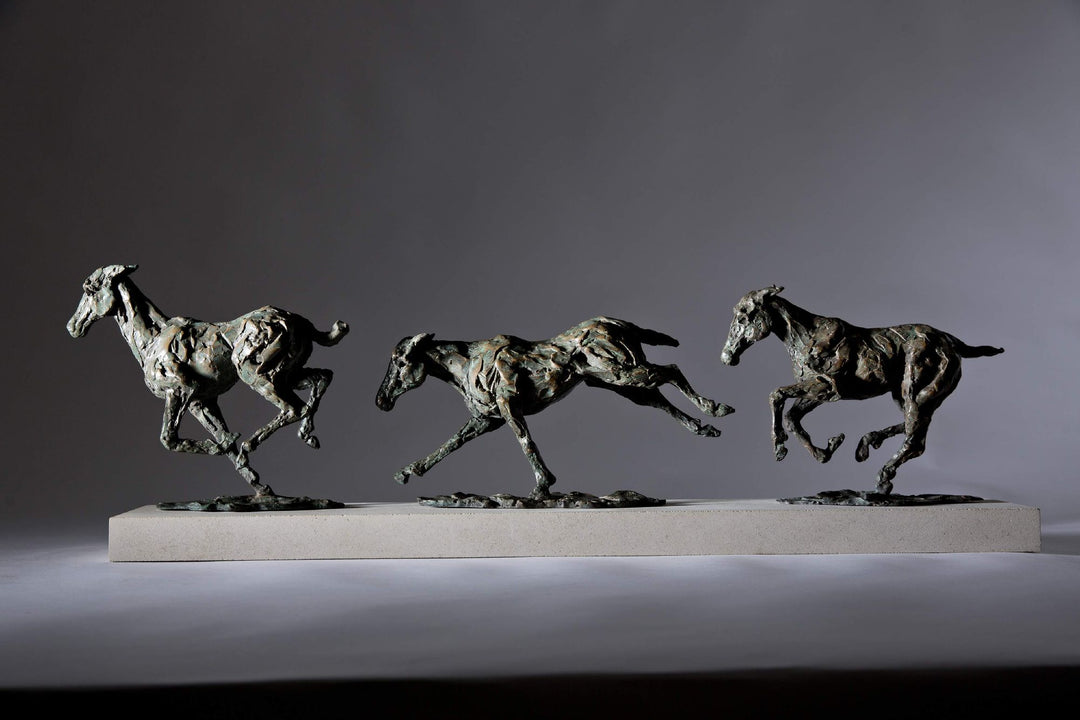 Bronze sculpture of three galloping horses mounted on a Portland stone base, capturing the fluid motion and changing form of equine movement in a verdigris finish.