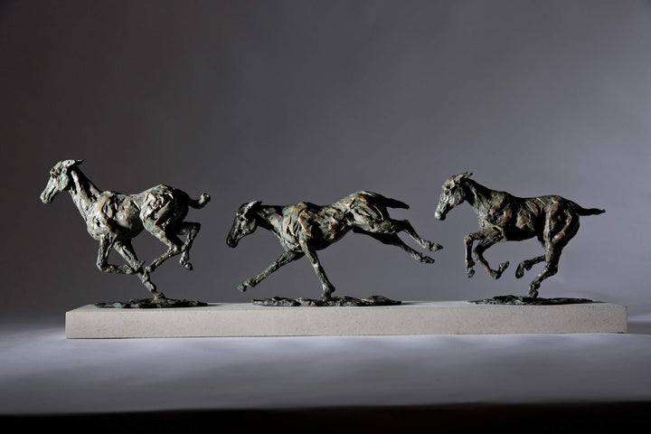 Bronze sculpture of three galloping horses mounted on a Portland stone base, capturing the fluid motion and changing form of equine movement in a verdigris finish.