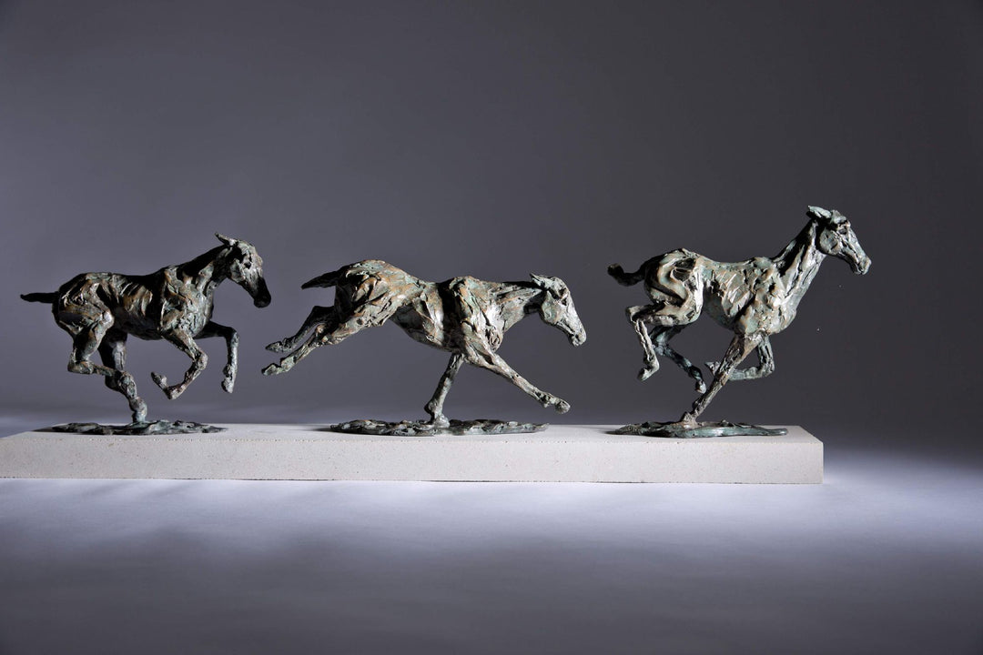 Bronze sculpture of three galloping horses mounted on a Portland stone base, capturing the fluid motion and changing form of equine movement in a verdigris finish.