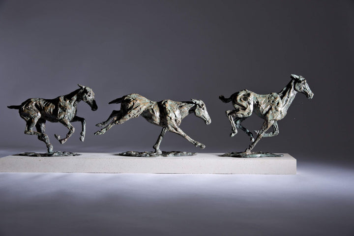 Bronze sculpture of three galloping horses mounted on a Portland stone base, capturing the fluid motion and changing form of equine movement in a verdigris finish.