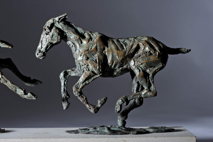 Bronze sculpture of three galloping horses mounted on a Portland stone base, capturing the fluid motion and changing form of equine movement in a verdigris finish.