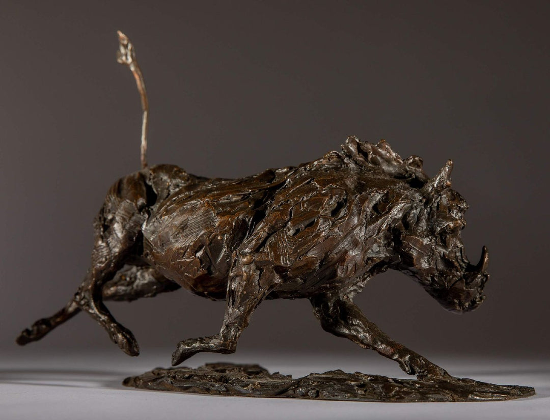 Bronze sculpture of a warthog mid-sprint with exaggerated texture and raised tail, captured in dynamic motion and set against a neutral backdrop.