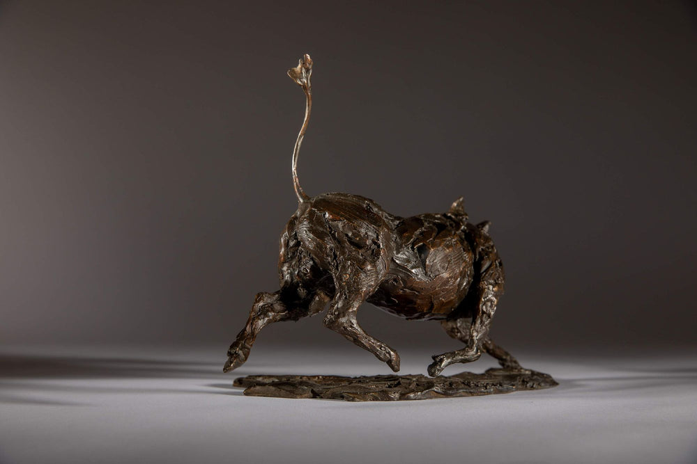 Bronze sculpture of a warthog mid-sprint with exaggerated texture and raised tail, captured in dynamic motion and set against a neutral backdrop.