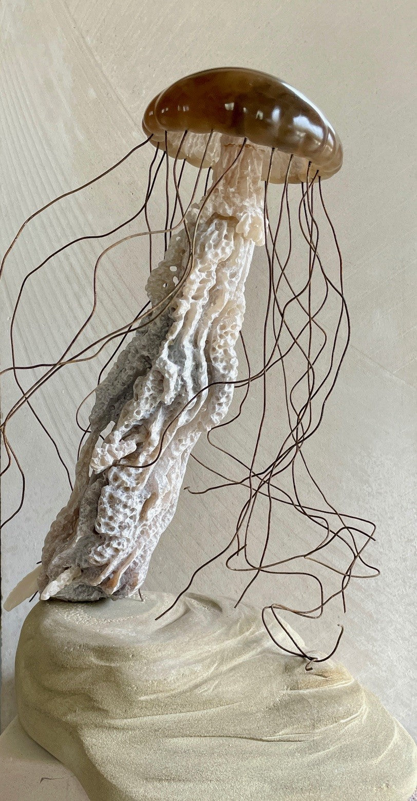 Sea Nettle Jelly sculpture by Nicola Axe — a graceful, hand-carved jellyfish with a translucent brown alabaster bell, organic ivory and beige stone body, and flowing rusted wire tentacles, rising from a softly contoured sandstone base.