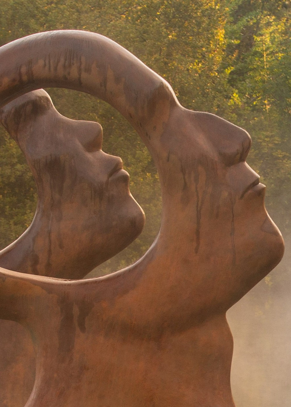 Simon Gudgeon bronze sculpture Search for Enlightenment featuring monumental interlocking abstract human forms with circular openings displayed within a landscaped outdoor setting.