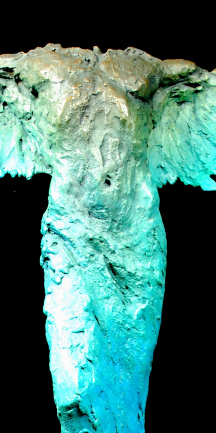 Tall contemporary bronze sculpture by Eve Shepherd depicting an elongated winged human form poised in stillness, with outstretched yet restrained wings, textured patinated bronze surface in turquoise and green tones, mounted on a vertical plinth and stone base, conveying calm, balance, contemplation and spiritual presence