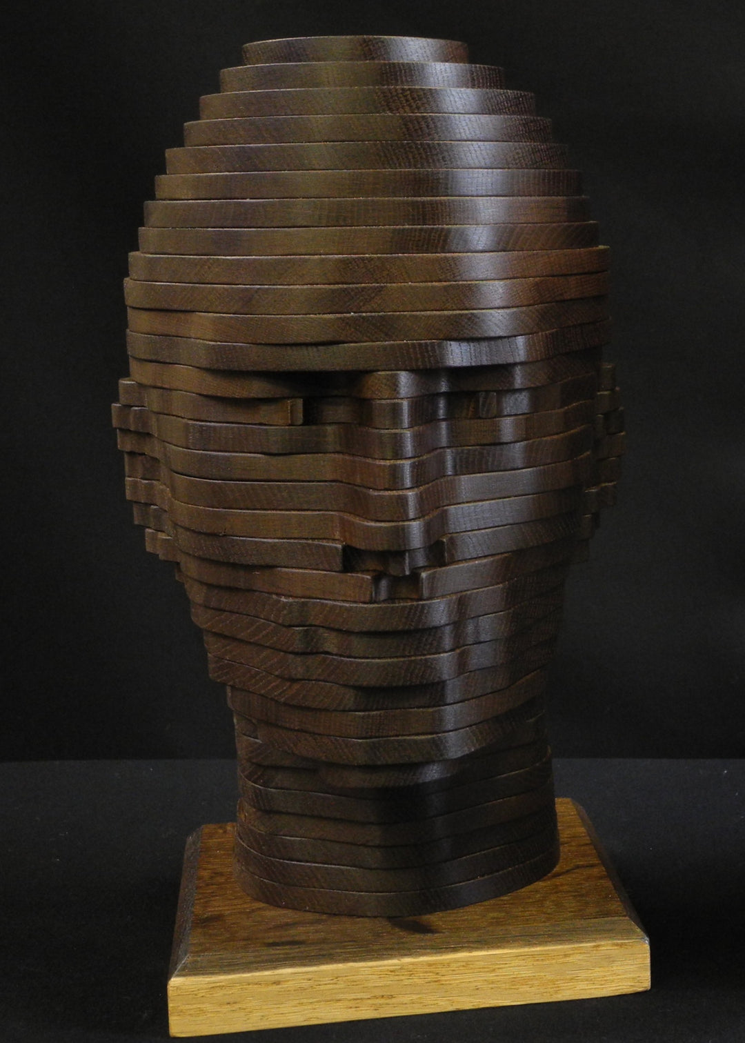 Sliced Heads by Max McCance, one-off layered wood sculptures in maple and fumed oak, forming two stylised busts with hand-shaped strata that reveal masculine and feminine features through geometric abstraction.