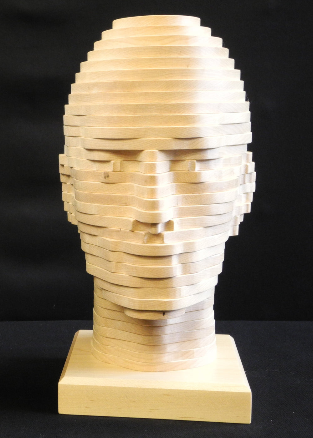 Sliced Heads by Max McCance, one-off layered wood sculptures in maple and fumed oak, forming two stylised busts with hand-shaped strata that reveal masculine and feminine features through geometric abstraction.