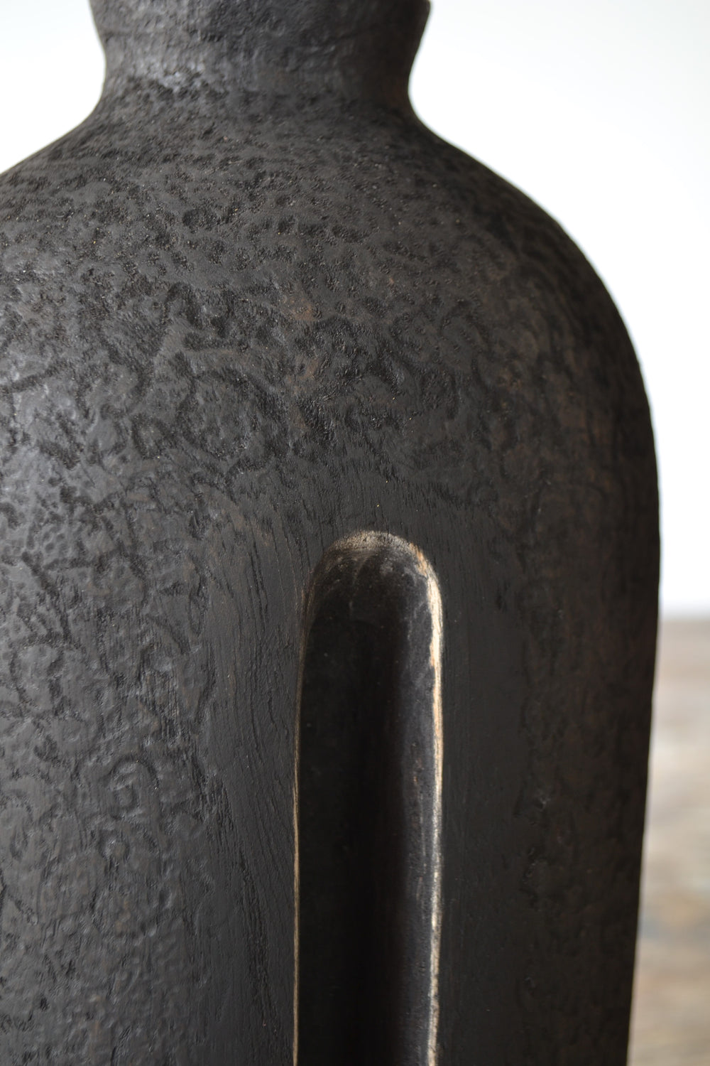 Solitude by Nicola Beattie – tall hand-carved sculpture in charred sycamore and bog oak, with elongated vertical form, deep central recess, and textured blackened surface on rugged base, evoking ancient standing stones and quiet resilience.