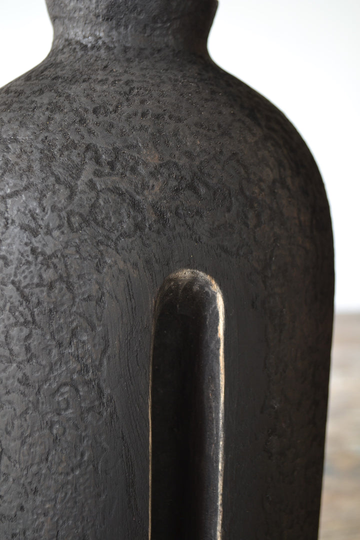 Solitude by Nicola Beattie – tall hand-carved sculpture in charred sycamore and bog oak, with elongated vertical form, deep central recess, and textured blackened surface on rugged base, evoking ancient standing stones and quiet resilience.