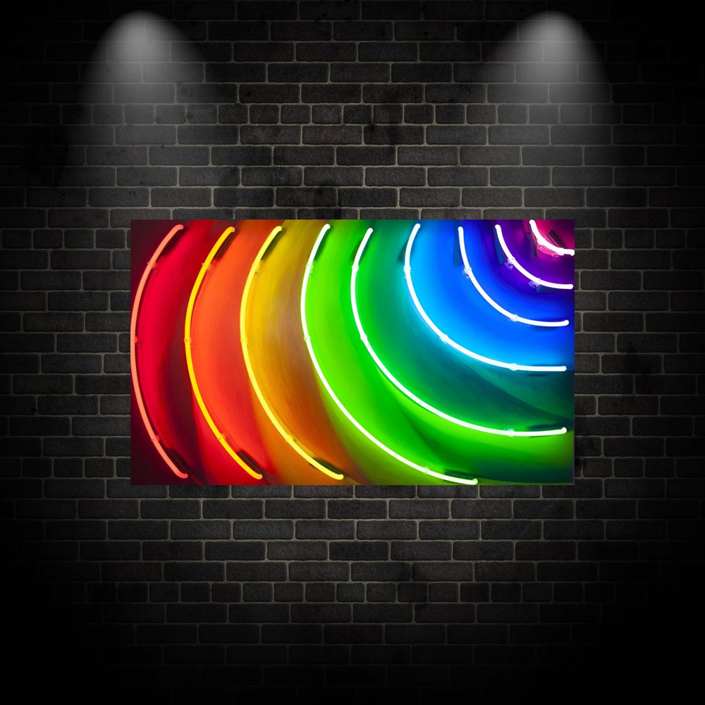 Curved neon light installation by Matthew Bracey forming a radiant spectrum across a wall, with glowing arcs in red, orange, yellow, green, blue, and violet. The light creates a dynamic rainbow effect that spills onto the surrounding surface, showcasing a bold and immersive colour experience.