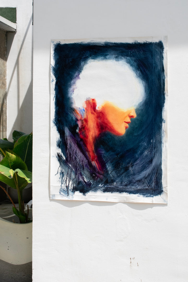 Oil on canvas painting by Dan Bullock, titled Spellbound. A semi-abstract portrait of a woman in profile, her face softly lit in warm peach and orange tones, contrasted against deep navy and indigo brushwork. The upper head dissolves into white light, creating a sense of mystery and transcendence. The expressive textures and layered brushstrokes convey both fragility and strength.