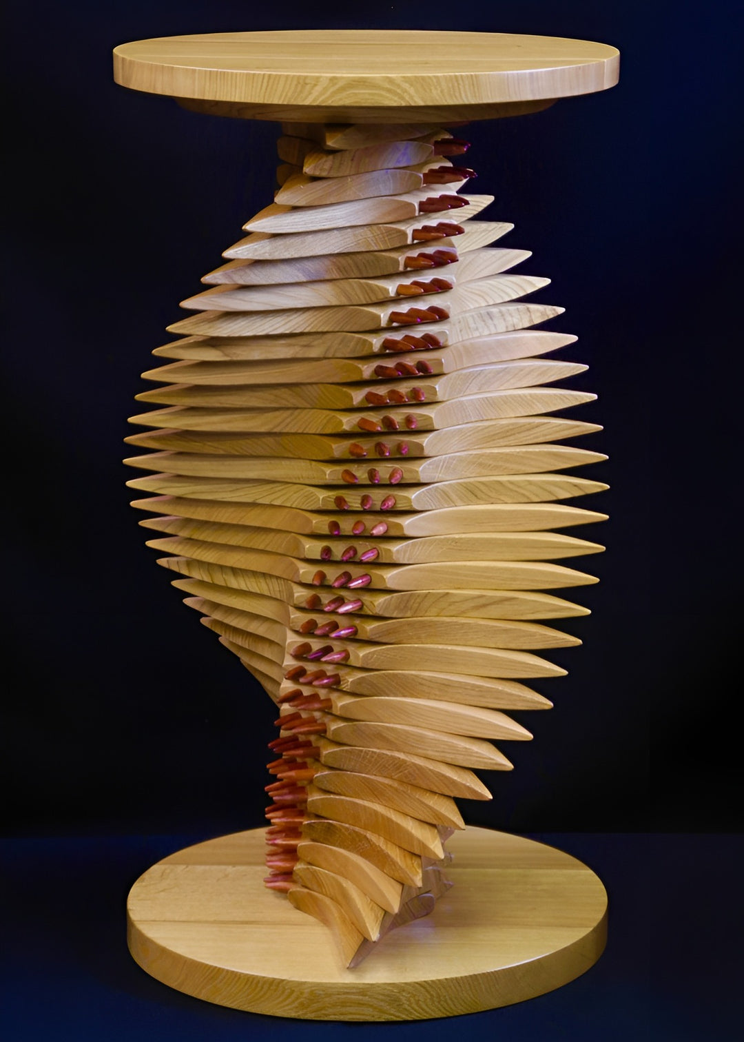 Sculptural oak and bubinga table with a twisting, spine-like form, its layered wooden structure punctuated by pointed red bubinga dowels that emphasise the gullet, creating rhythm, balance, and technorganic tension.