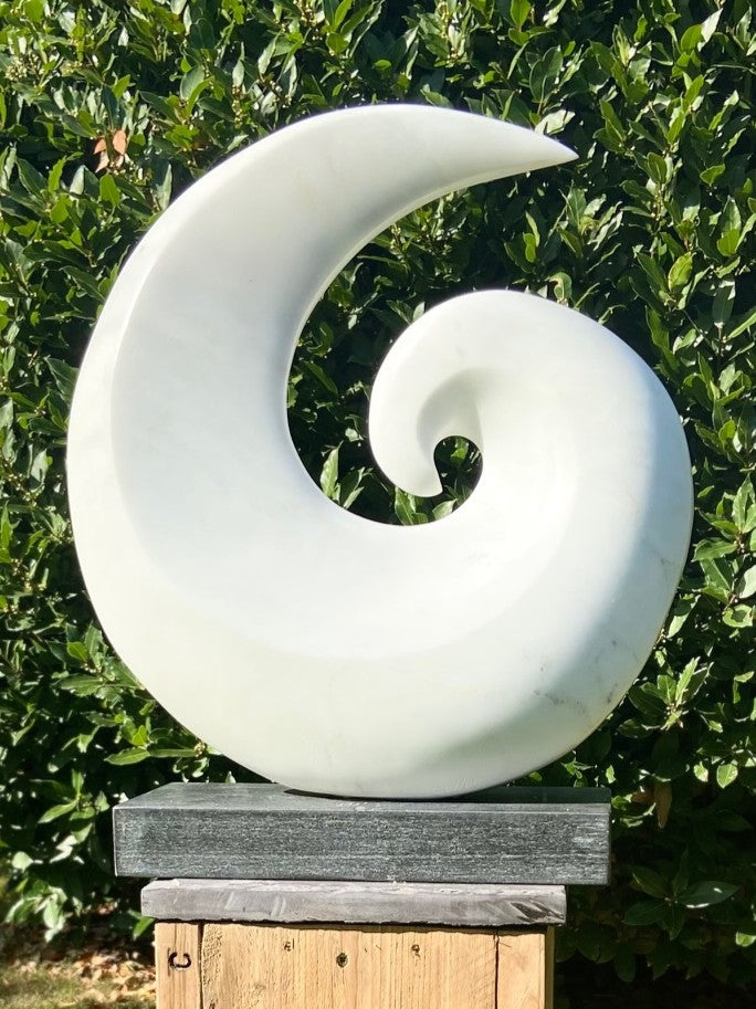 Spiral by Brendan Cullen, hand-carved from Statuario Marble, a smooth white sculpture in a curling spiral form with flowing curves and polished surface, mounted on a dark stone base.