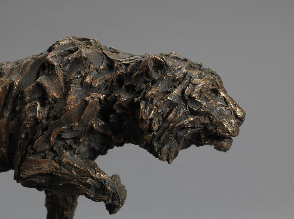 Bronze sculpture of a stalking tiger with heavily textured, abstract surface detail, mounted on a dark rectangular base