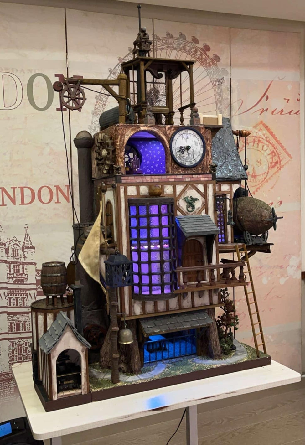 Illuminated steampunk-style dolls house with gears, dials, glowing purple windows, and intricate handcrafted architectural details.