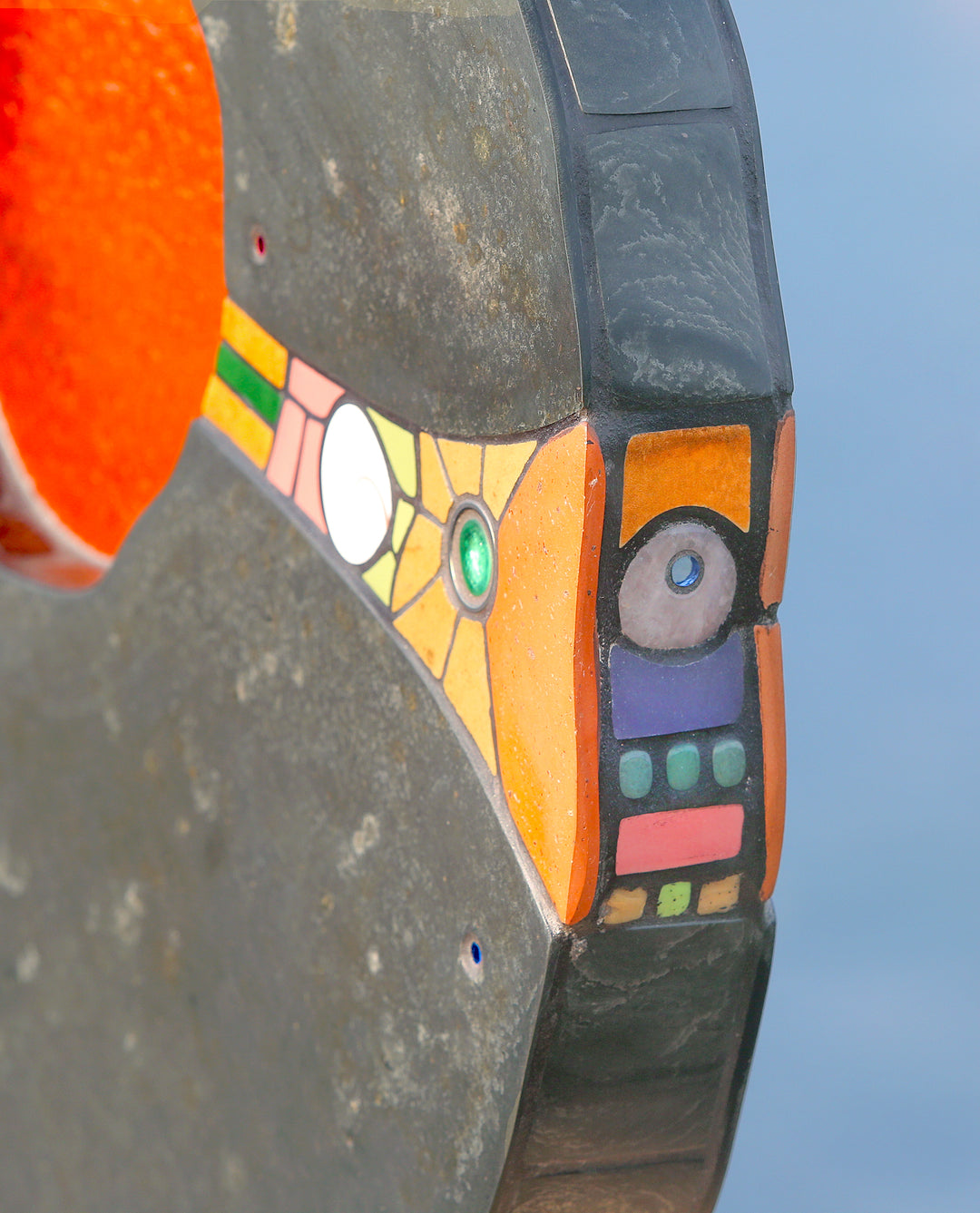 Slate and glass sculpture by Stacey Beaumont titled Sundancer, featuring reclaimed Delabole slate with a glowing amber-orange glass core, inlaid with sea-glass, fossils, ceramics, gemstones, and gold leaf, inspired by coastal light.