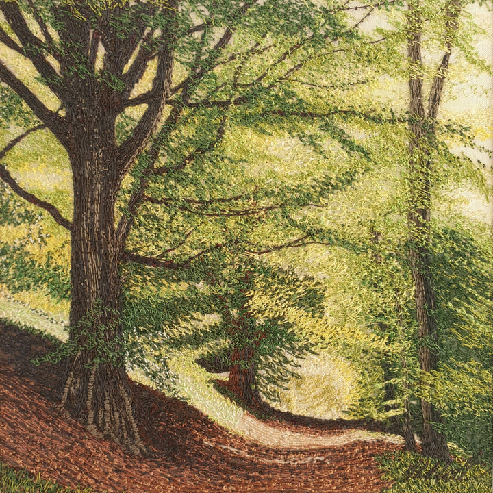 Intricately embroidered woodland scene with sunlit trees and a winding path through a leafy forest.

