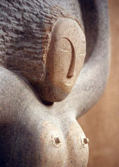 ‘Sunrise’ by Nicolas Moreton MRSS, a unique contemporary figurative stone sculpture carved from Ancaster Weatherbed Limestone, depicting a stylised seated female figure with crossed legs and raised arms forming a circular halo-like shape above her head. The figure features a delicately carved face, textured hair and smooth, rounded body, emerging from a large rectangular limestone block with a rough natural surface and flowing carved folds. Finished in warm cream, pale beige and natural limestone tones, the