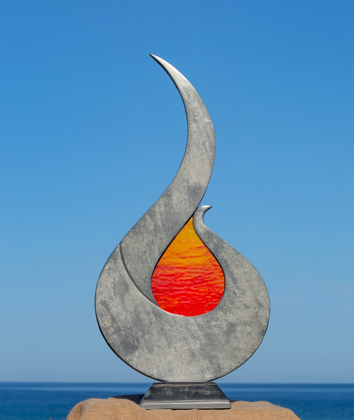 Stacey Beaumont Sunstone slate and glass sculpture, a flame-like form in reclaimed Delabole slate with textured orange and red glass centre inspired by Atlantic sunsets.