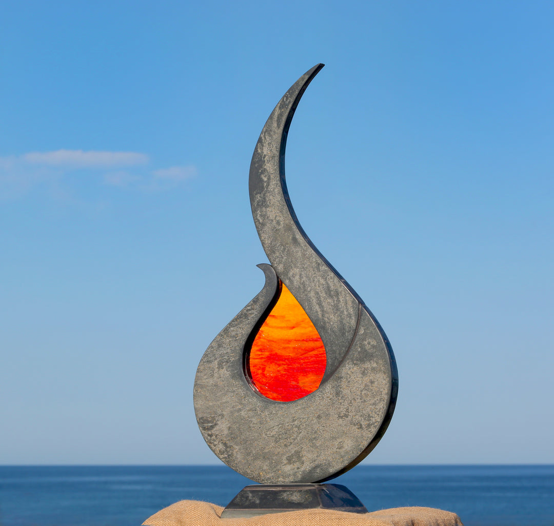 Stacey Beaumont Sunstone slate and glass sculpture, a flame-like form in reclaimed Delabole slate with textured orange and red glass centre inspired by Atlantic sunsets.