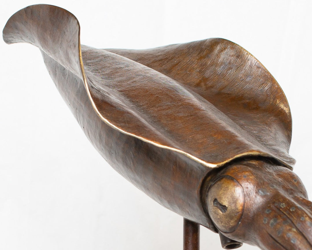 Bigfin Reef Squid bronze sculpture by Tom Saxton mounted on a vertical stand and Cotswold stone plinth, elegant marine life sculpture with flowing fins in rich dark bronze and warm copper-brown tones with subtle golden highlights