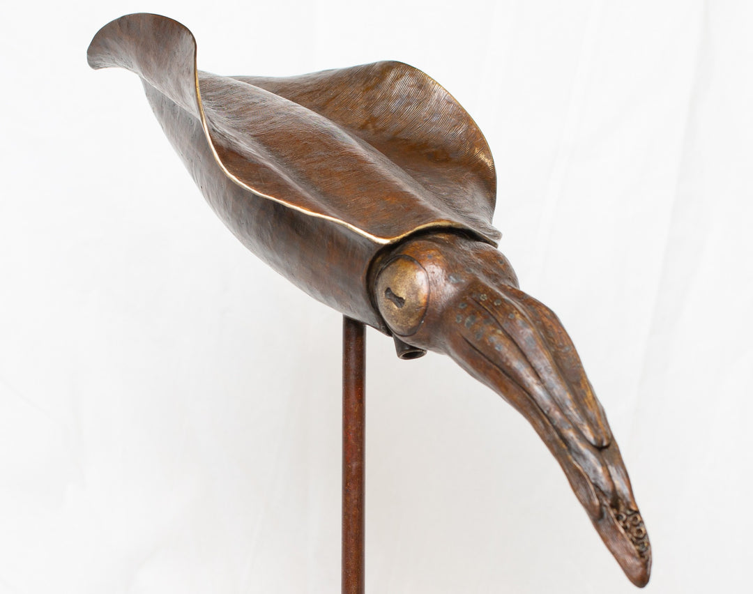 Bigfin Reef Squid bronze sculpture by Tom Saxton mounted on a vertical stand and Cotswold stone plinth, elegant marine life sculpture with flowing fins in rich dark bronze and warm copper-brown tones with subtle golden highlights