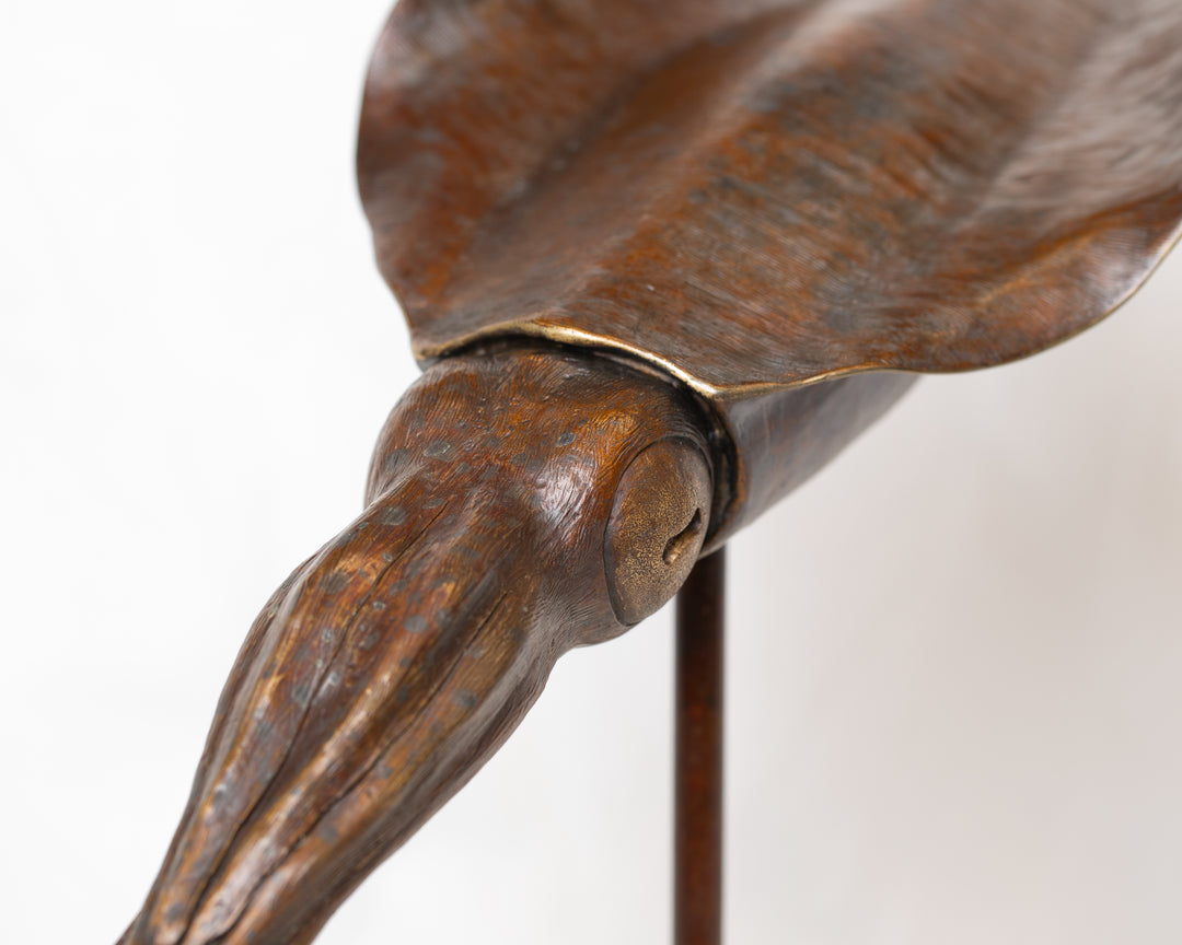 Bigfin Reef Squid bronze sculpture by Tom Saxton mounted on a vertical stand and Cotswold stone plinth, elegant marine life sculpture with flowing fins in rich dark bronze and warm copper-brown tones with subtle golden highlights