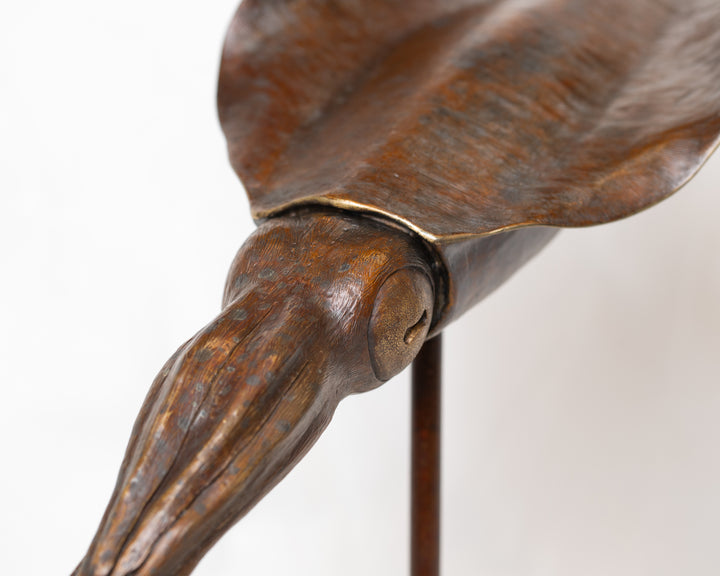 Bigfin Reef Squid bronze sculpture by Tom Saxton mounted on a vertical stand and Cotswold stone plinth, elegant marine life sculpture with flowing fins in rich dark bronze and warm copper-brown tones with subtle golden highlights