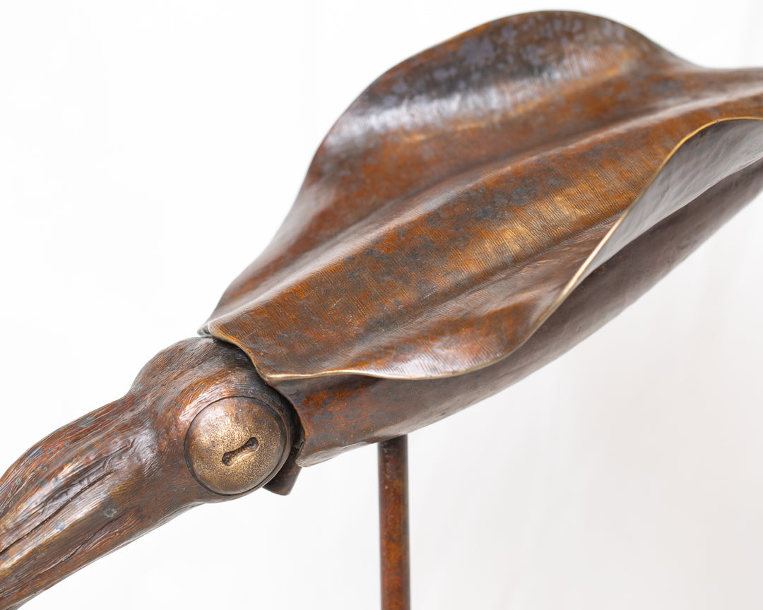 Bigfin Reef Squid bronze sculpture by Tom Saxton mounted on a vertical stand and Cotswold stone plinth, elegant marine life sculpture with flowing fins in rich dark bronze and warm copper-brown tones with subtle golden highlights