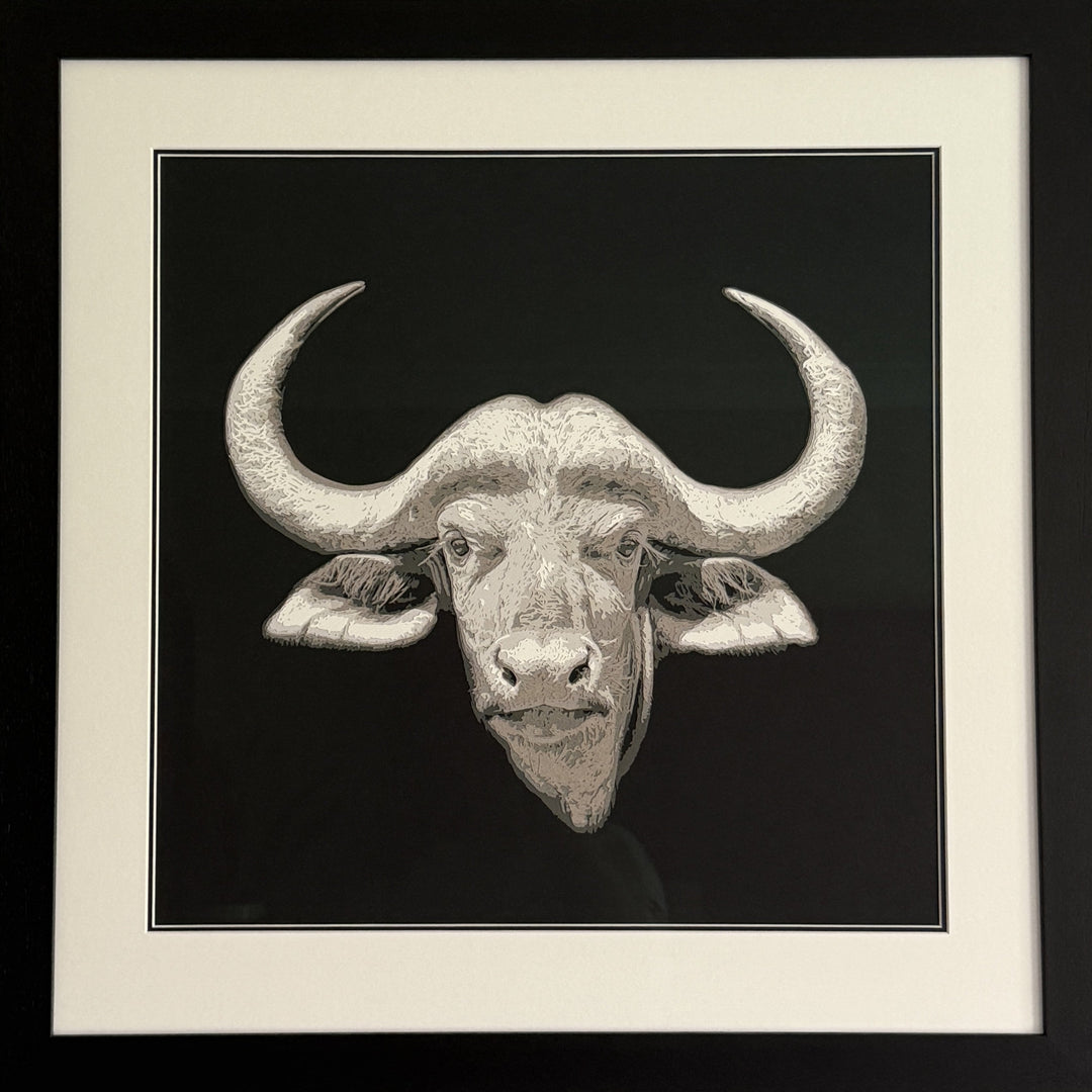 Hand-cut paper artwork of a Cape buffalo head with sweeping horns, crafted from eight layers in tones of ivory, stone grey, and warm taupe. The calm, commanding gaze captures strength and resilience, framed in black wood with UV-protective art glass.