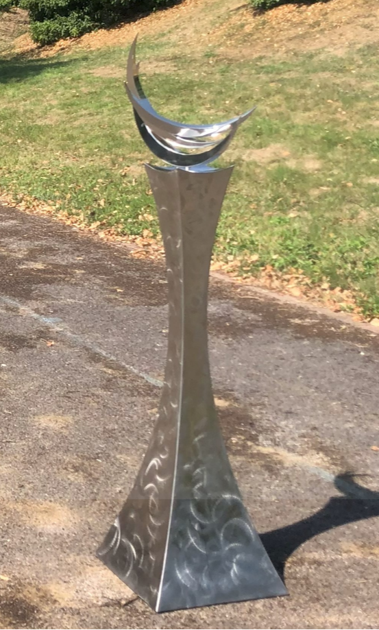 Martin Jarvis’ The Crescent Trinity (Edition 1 of 10), kinetic sculpture in 316 stainless steel with sealed ball race bearings. Standing 1.5m tall, the polished triple crescent form rises from a textured, flared base, rotating gracefully when touched or moved by wind.