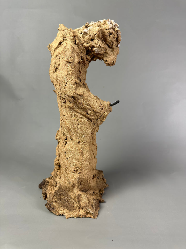 Ceramic figurative sculpture by Eve Shepherd depicting a solitary seated, animal-like figure hunched forward and absorbed in a mobile phone, rendered in rough-textured fired clay with an earthy, sand-coloured surface, capturing contemporary isolation, digital distraction, and quiet introspection through raw, observational form.