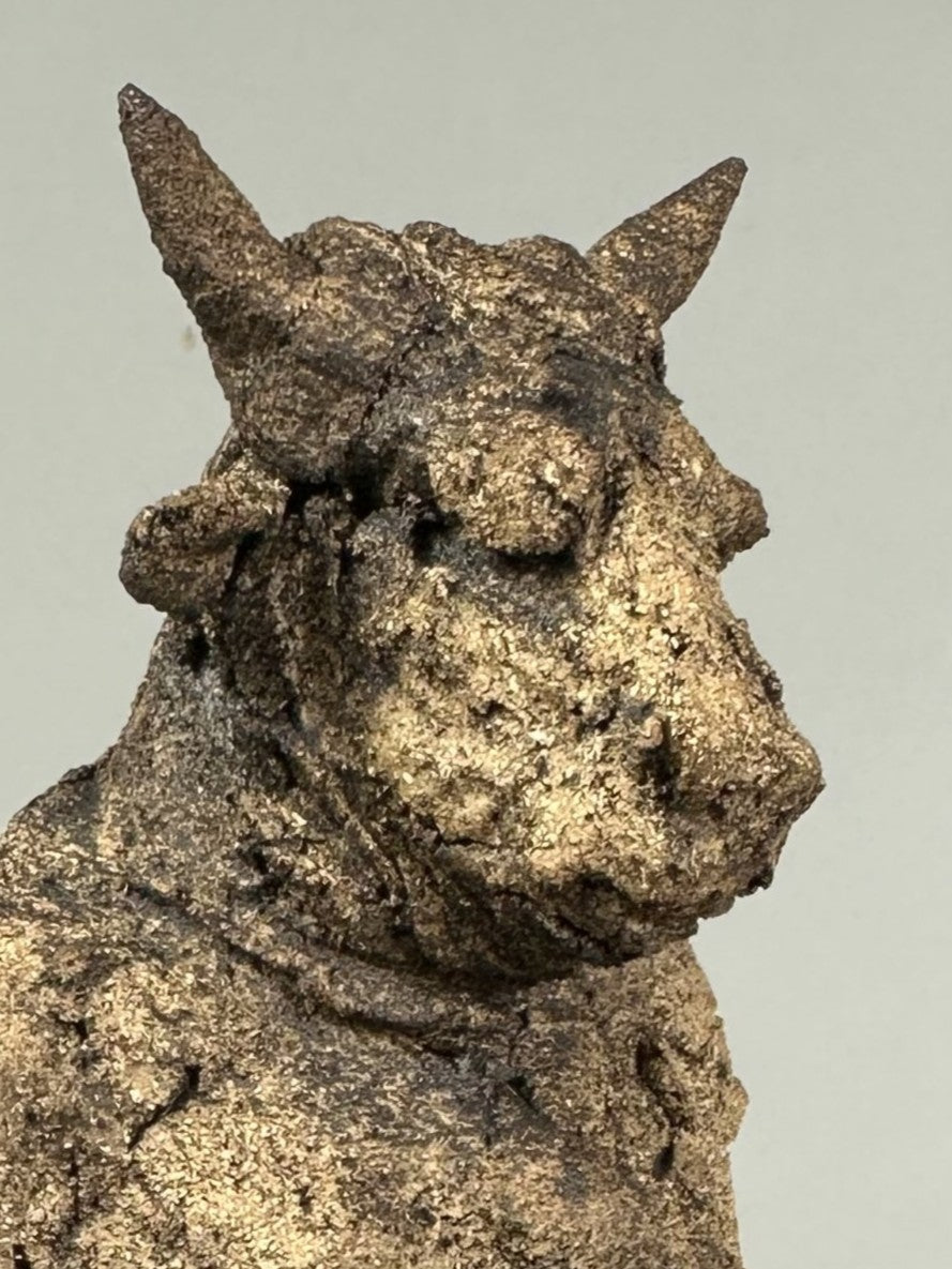 Figurative ceramic sculpture of a crouched animal-like figure absorbed in a mobile phone, exploring modern distraction and isolation, by Eve Shepherd