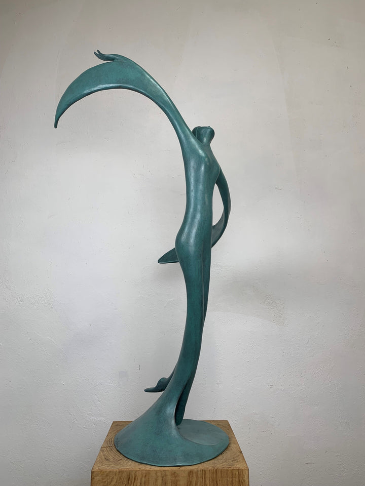 Abstract teal bronze sculpture of a flowing female figure with elongated arms and sweeping wing-like forms, suggesting flight or dance.