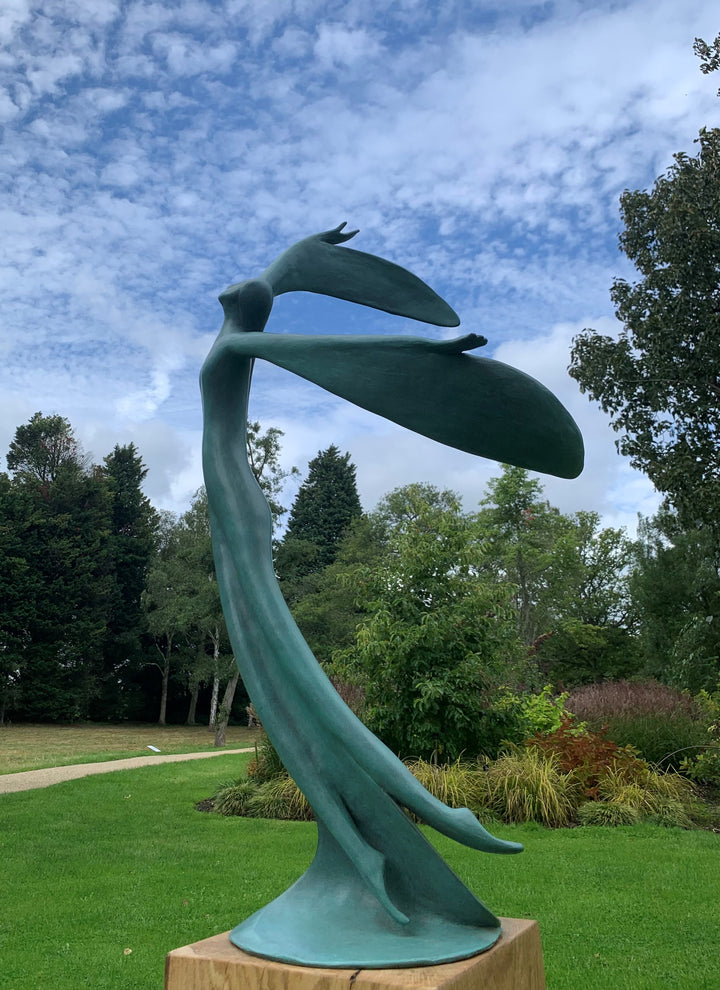 Abstract teal bronze sculpture of a flowing female figure with elongated arms and sweeping wing-like forms, suggesting flight or dance.