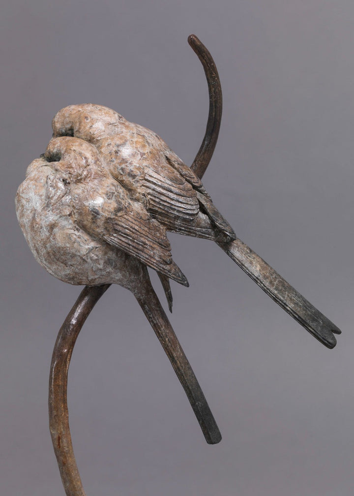 A delicate bronze sculpture of two long-tailed tits nestled together on a sweeping branch, their rounded forms and soft patinated tones capturing warmth, intimacy and the gentle character of these much-loved British birds.