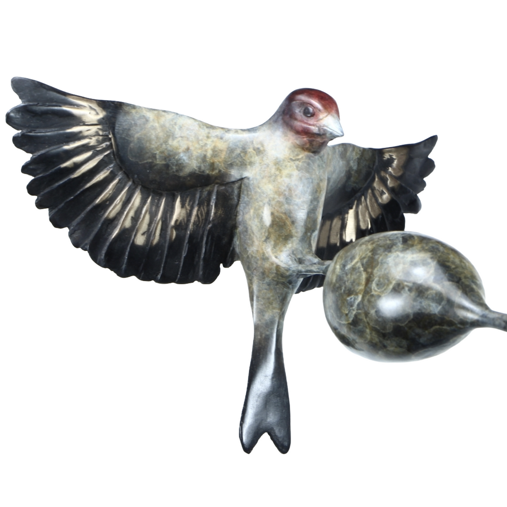 ‘Thistle Tweaker’ by Pat Bull, a limited-edition contemporary bronze wildlife sculpture depicting a goldfinch landing on a rounded teasel head with its wings fully outstretched. The bird features individually detailed bronze feathers, a distinctive reddish-brown face, dark wings with subtle bronze highlights and a forked tail. The teasel head is supported by a slender, sweeping curved steel stem rising from a rectangular bronze base, with dark grey, charcoal and muted green patina tones creating an elegant 