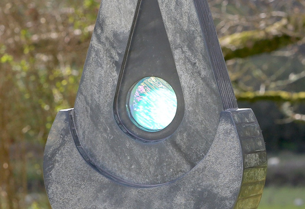Stacey Beaumont slate and glass sculpture Ti-Pedin, a tall triangular form in reclaimed Delabole and French slate with carved detail and an iridised blue glass centre, inspired by sacred spaces and reflection.