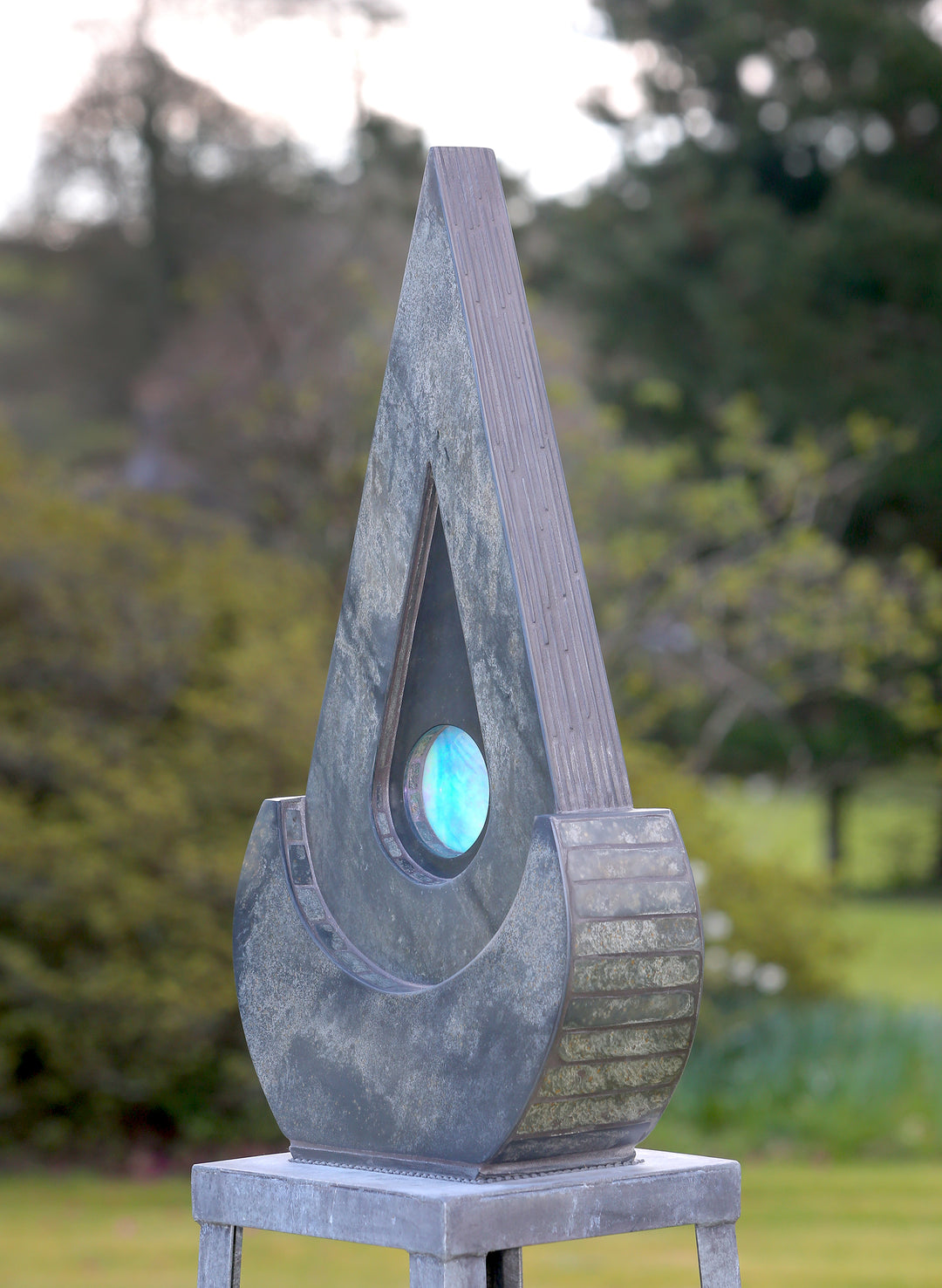 Stacey Beaumont slate and glass sculpture Ti-Pedin, a tall triangular form in reclaimed Delabole and French slate with carved detail and an iridised blue glass centre, inspired by sacred spaces and reflection.