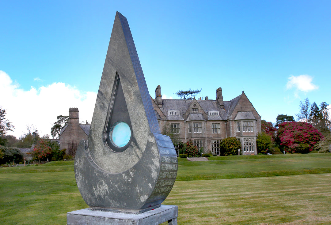 Stacey Beaumont slate and glass sculpture Ti-Pedin, a tall triangular form in reclaimed Delabole and French slate with carved detail and an iridised blue glass centre, inspired by sacred spaces and reflection.