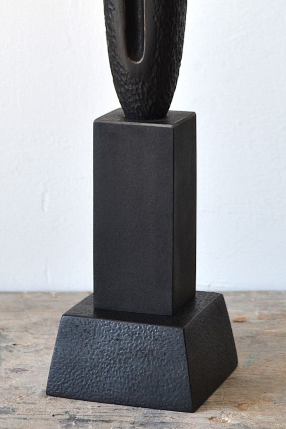 TORR by Nicola Beattie – tall, slender walnut sculpture with textured, rounded form and deep central vertical recess, mounted on a solid stepped base. Rich dark brown finish with natural grain, evoking ancient totems and minimalist modern design.