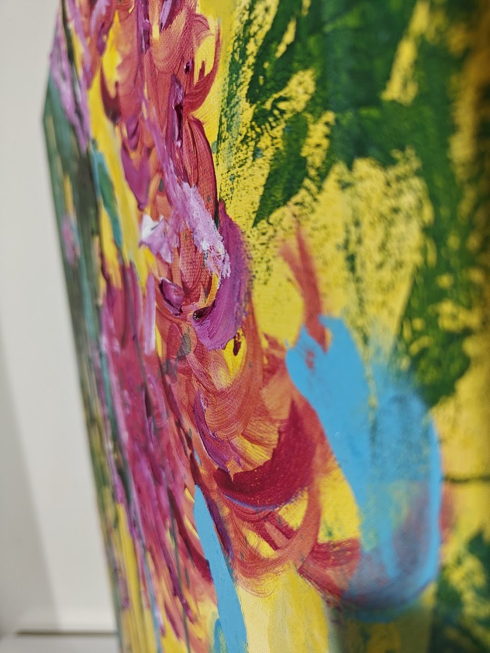 Vivid abstract painting with bold magenta florals, dripping green strokes, and splashes of blue over a bright yellow background