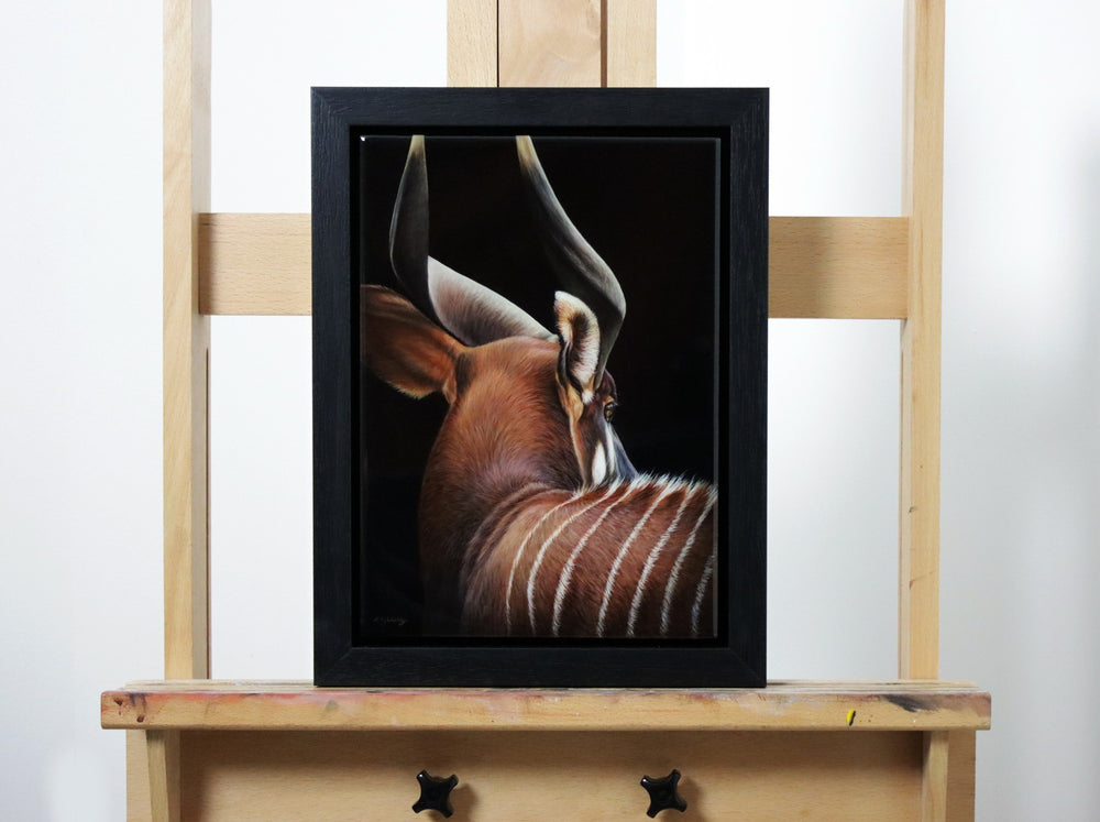 Hyperrealistic painting of a bongo antelope viewed from behind, showcasing its spiralled horns, russet coat, and white stripes against a deep black background.